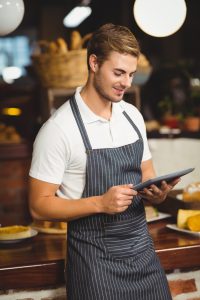 Handsome waiter using a tablet at the coffee shop Handsome waiter using a tablet at the coffee shop