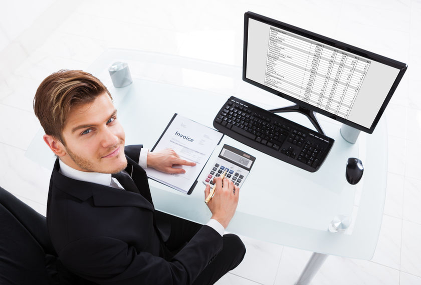 Businessman Calculating Expenses At Office Desk